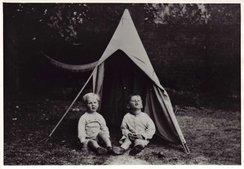 Leonard and Christopher Cheshire as young boys sat in front of a tent in a garden