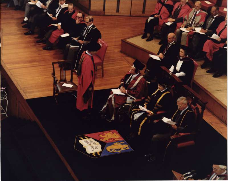 Leonard Cheshire on a stage in robes receiving a doctorate