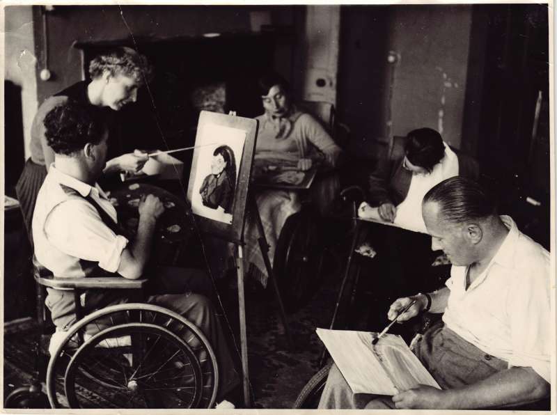 Several people in wheelchairs creating paintings and artwork