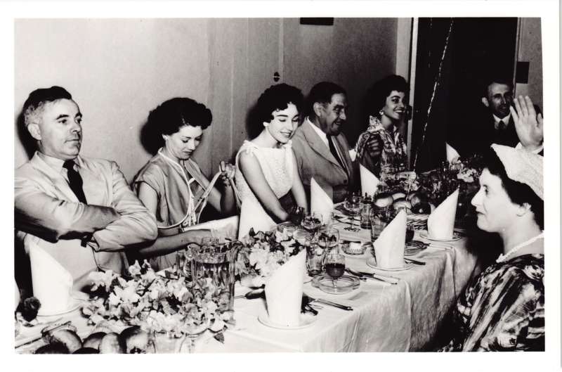 A group of men and women in smart clothes sat at a dressed dinner table