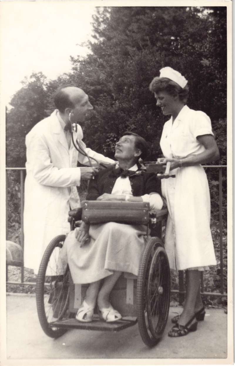 A woman in a wheelchair smiling at a man pretending to be a doctor with a nurse standing next to them