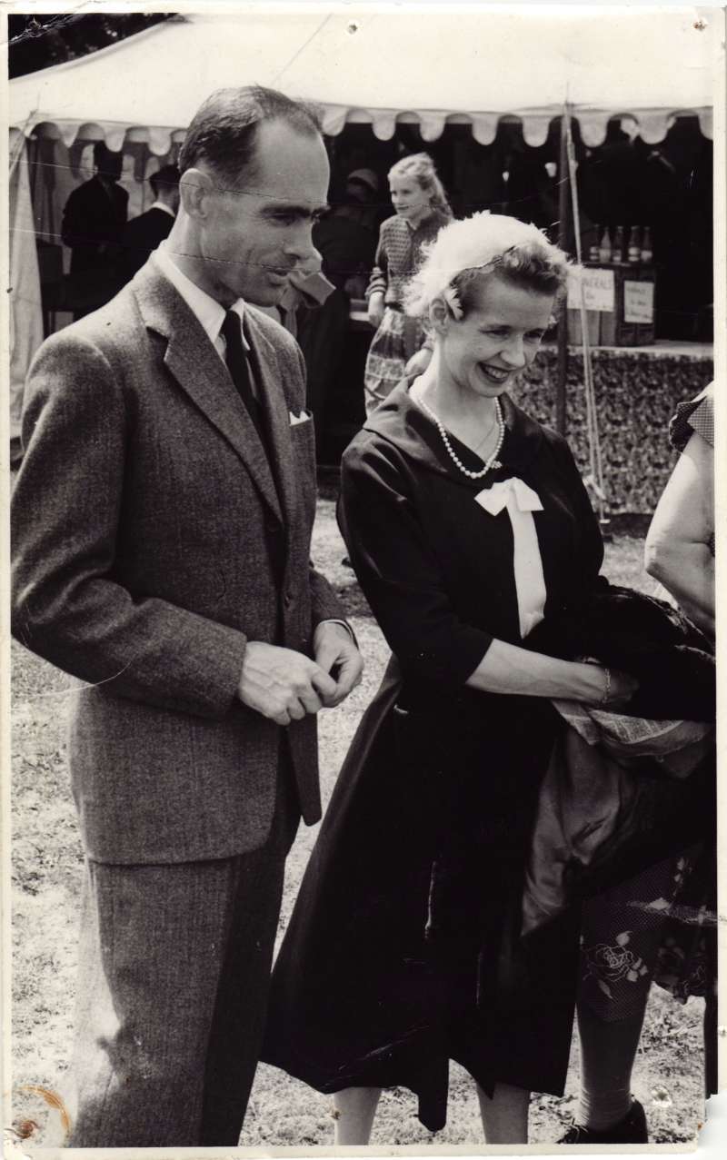 A young Leonard Cheshire and Sue Ryder in smart clothes standing outside a marquee smiling