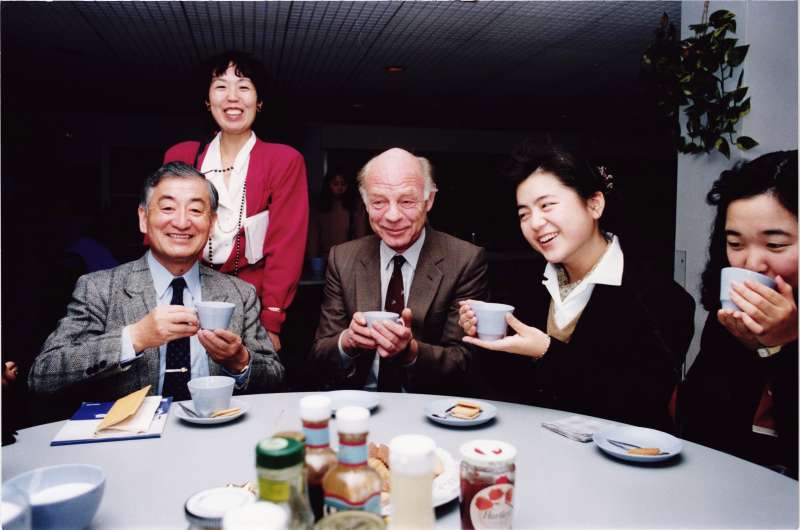 A man at a table with several Japanese visitors drinking tea