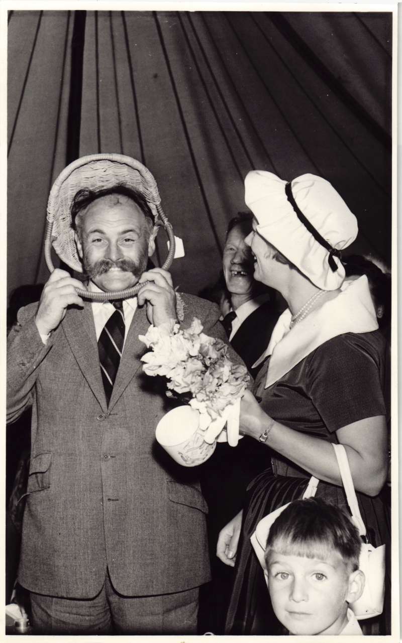 A man pretending to hold an upside down basket over his head with a woman laughing next to him
