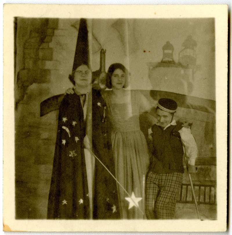 A man dressed in a wizard outfit, a woman in a long flowing dress and a shorter man in a bellboy costume