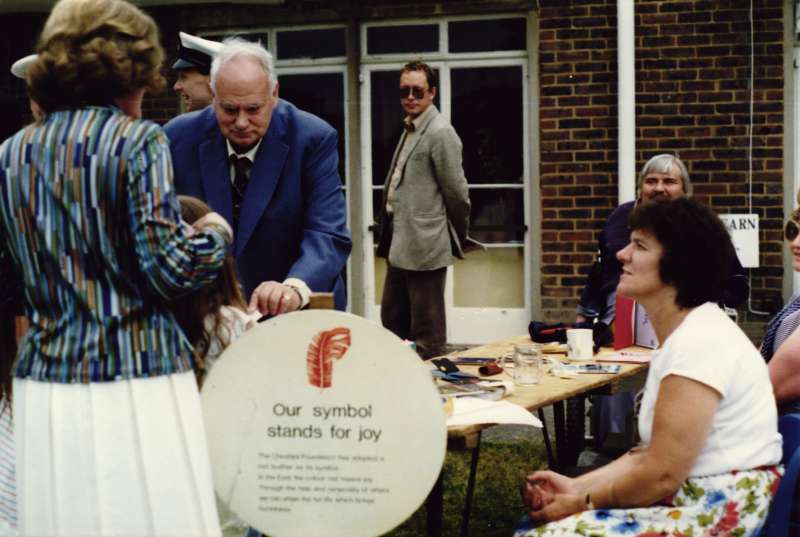 Patrick Moore shown giving something to a little girl with others in the background