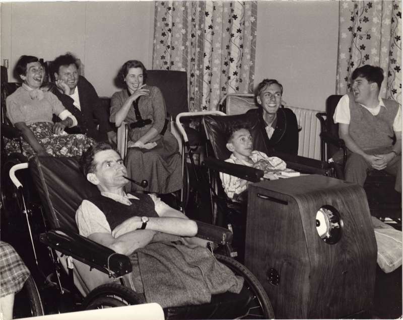 A group of people laughing at a programme on television