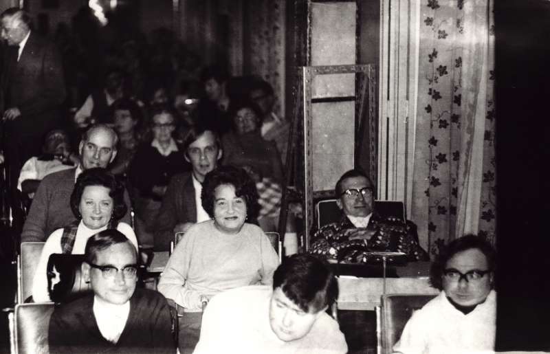 A group of people in seats and wheelchairs gathered for an event inside Le Court