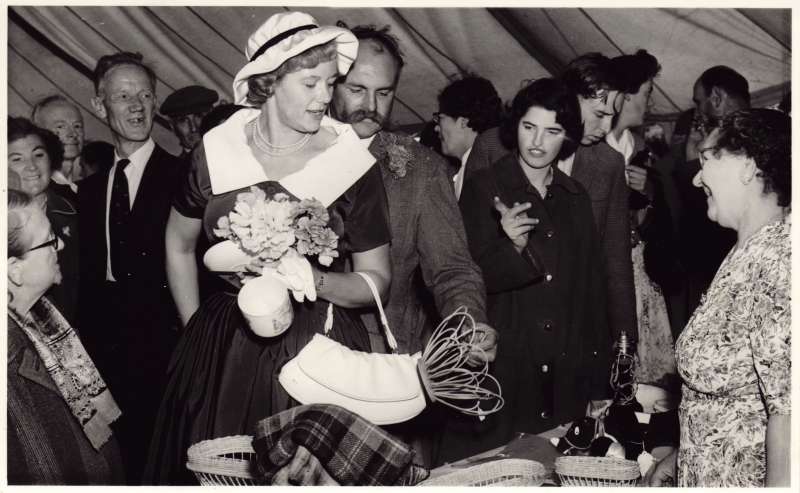 A man and woman inside a marquee looking at items on a craft stall