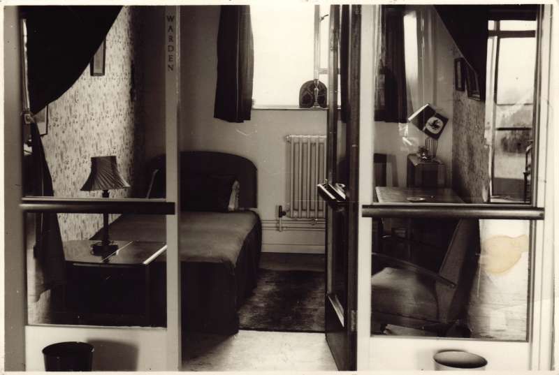 Photo of a bedroom for guests, showing a bed, table lamps, bedside table and armchair