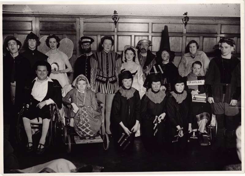 Group of people in fancy dress, some in wheelchairs, in a posed photo