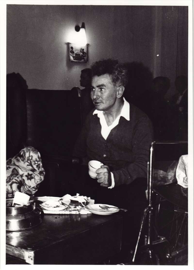 Man in a wheelchair at a table, holding a tea cup.