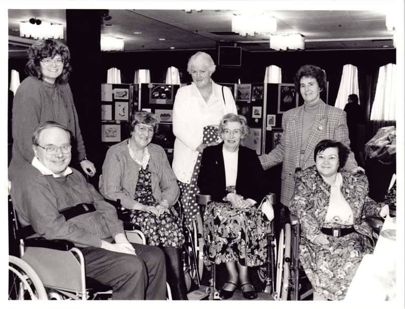Four residents in wheelchairs and three staff members at a crafts awards event