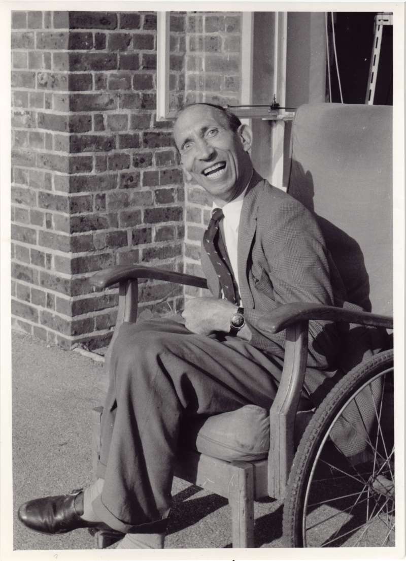 A smiling man sitting in an armchair outside