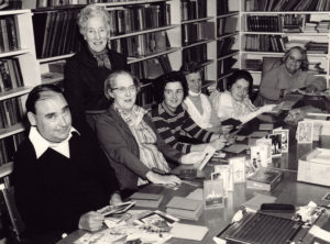 A group of people sat in a library surrounded by Christmas cards